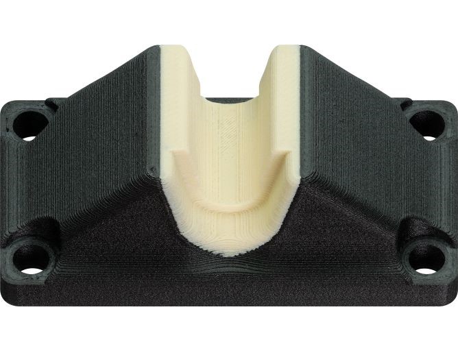 A 3D printed lead screw support block made of two different materials, a fiber-reinforced filament for the base and a tribo-filament for the bearing contact surface
